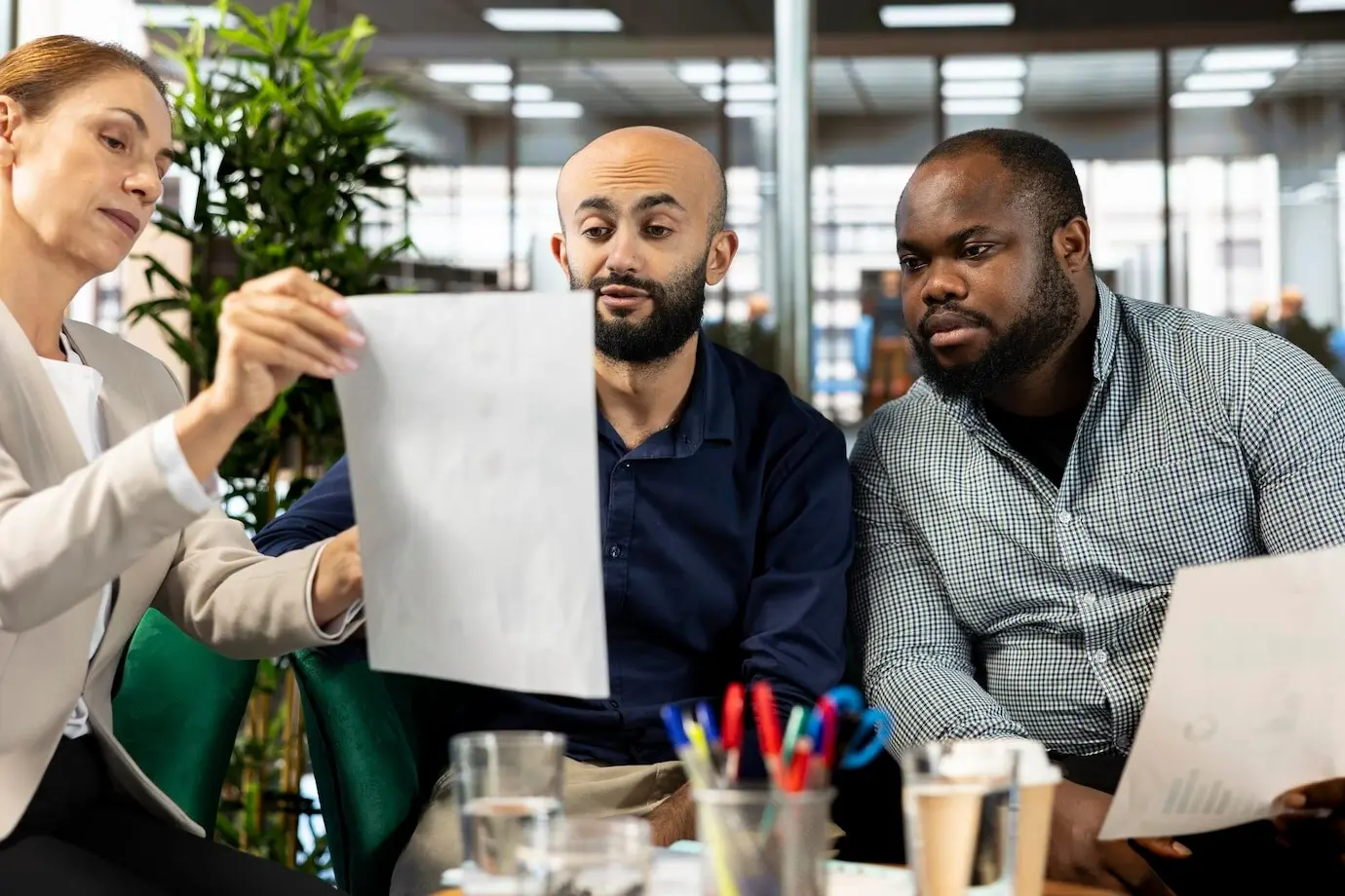 A diverse team of employees in an office speaking with a director while presenting progress.
