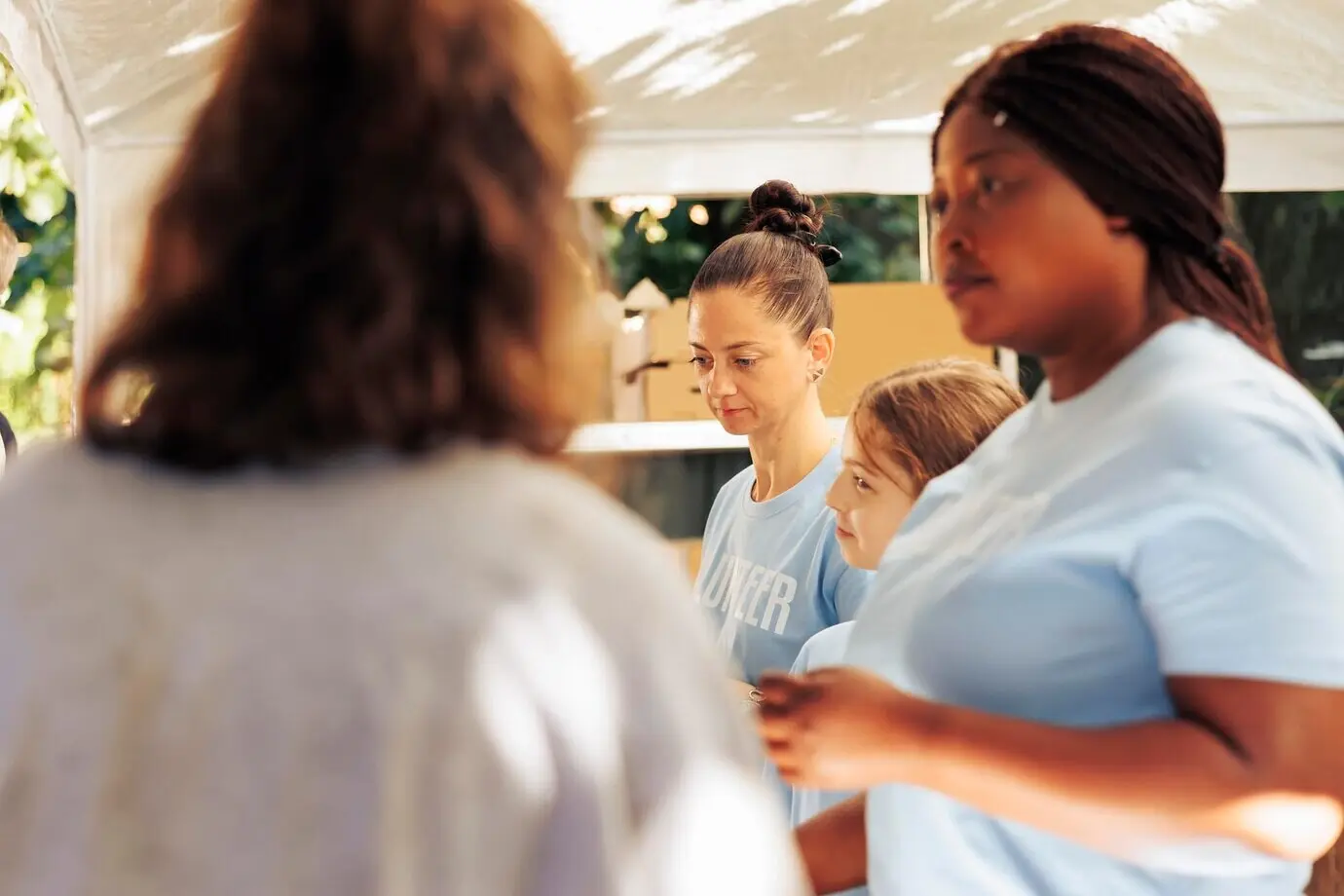 Image depicting a female volunteer team at a charity center handing out free food to less privileged people in the vicinity. Volunteers are seen helping poor and homeless individuals.